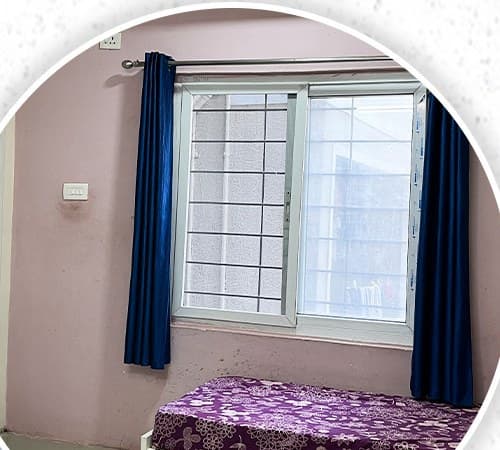 Room with a large window and curtains in the women's block